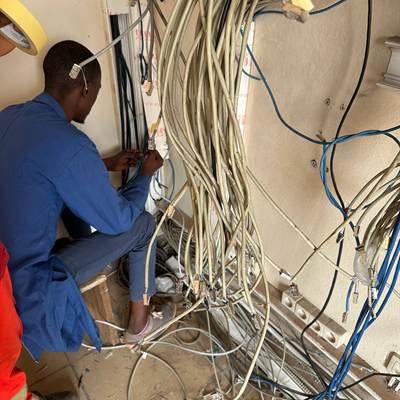 Technicien GORDAN POWER reprenant un faisceau de câbles réseau dans le local technique