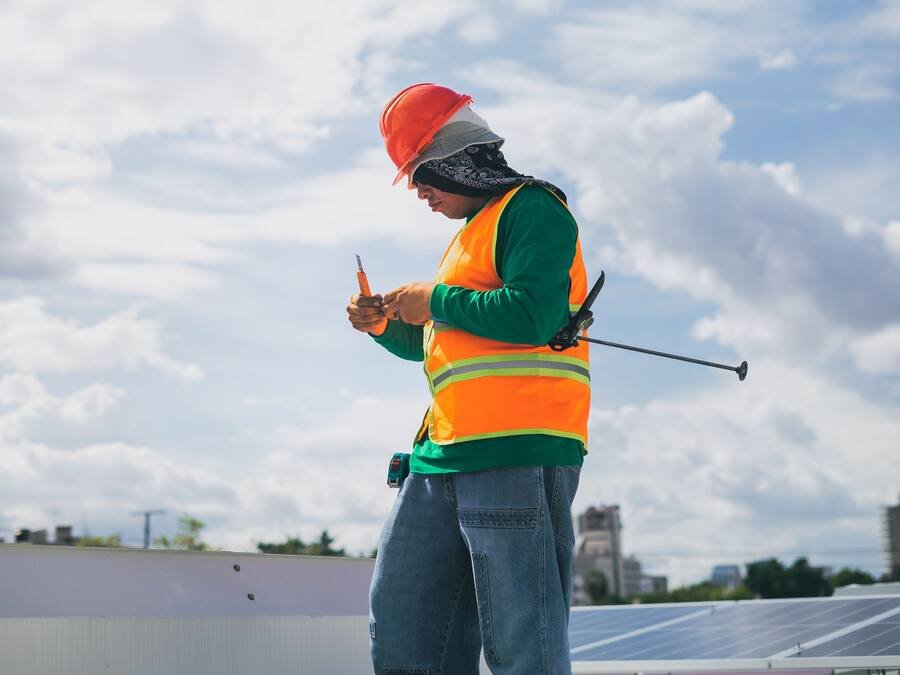 Technicien casqué relevant une mesure sur une installation photovoltaïque en toiture