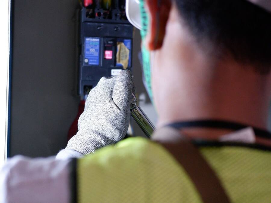 Technicien ganté intervenant sur les protections d’un tableau électrique