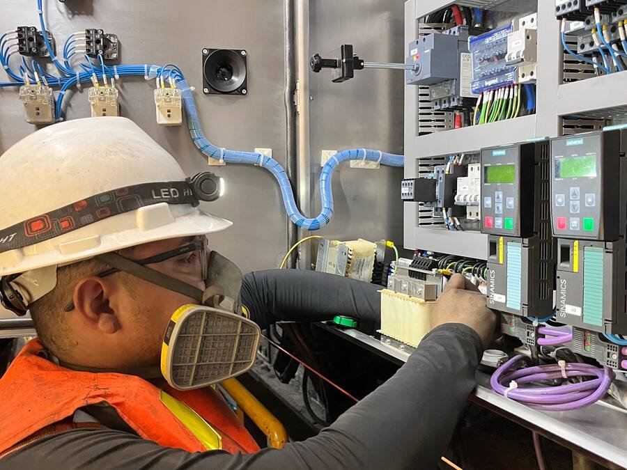 Technicien casqué intervenant à l’intérieur d’une armoire électrique industrielle