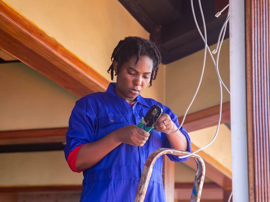 Jeune électricienne en tenue de travail raccordant des conducteurs