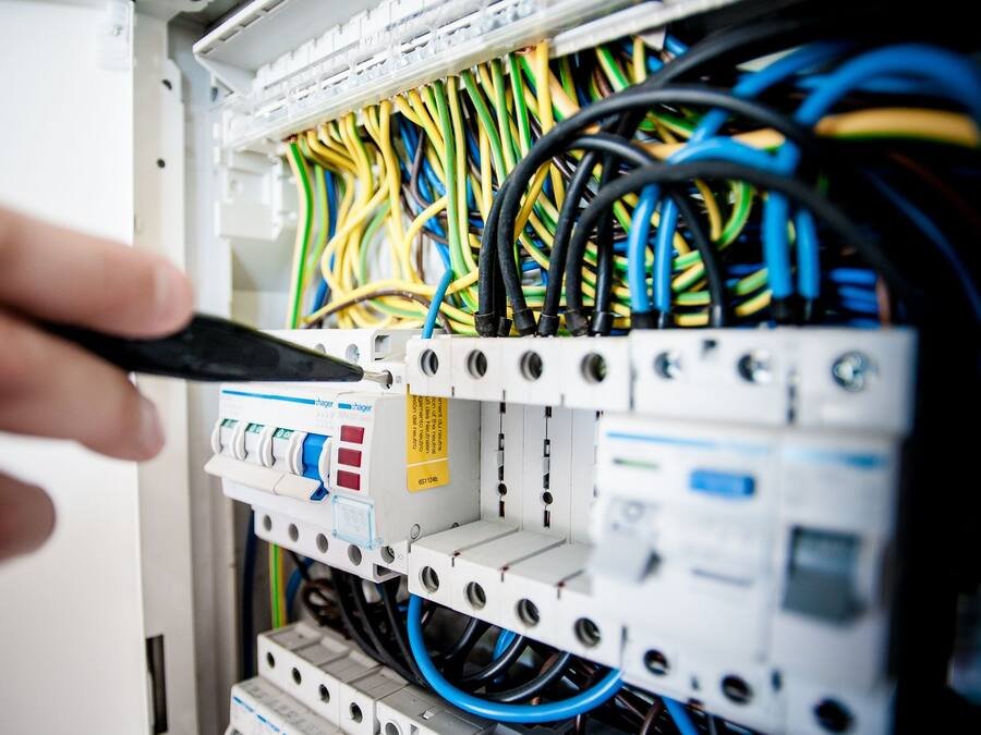 Électricien intervenant au tournevis sur un tableau électrique ouvert
