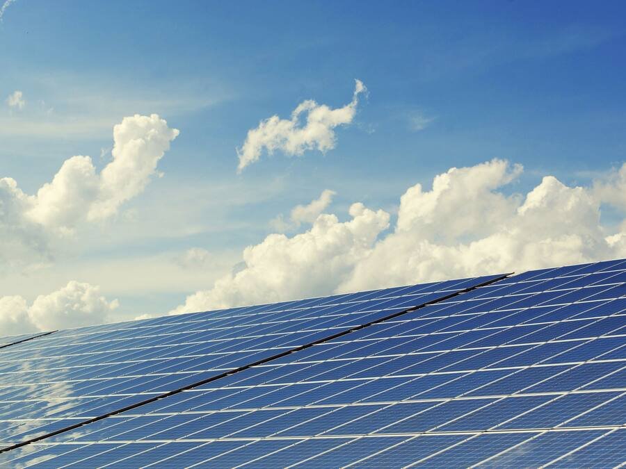 Rangée de panneaux photovoltaïques inclinés sous un ciel bleu nuageux