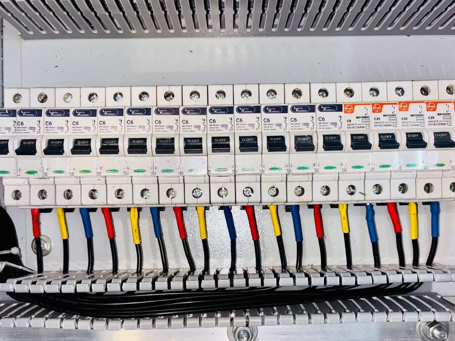 Rangée de disjoncteurs d’un tableau électrique au câblage repéré par couleurs