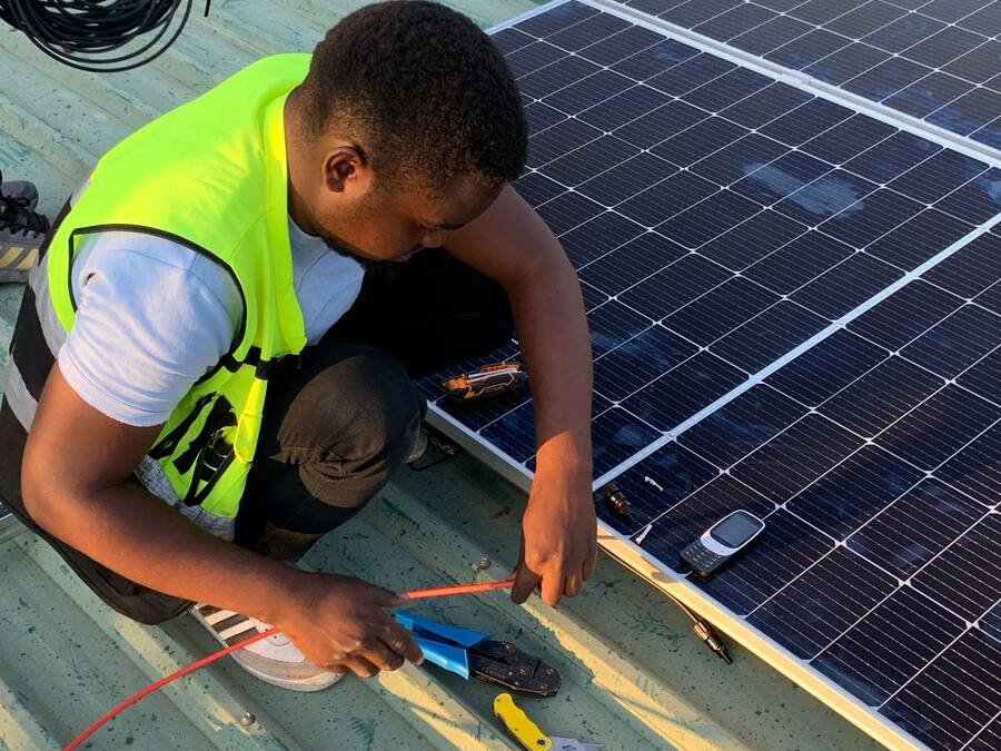 Technicien raccordant les câbles d’un panneau solaire sur une toiture métallique